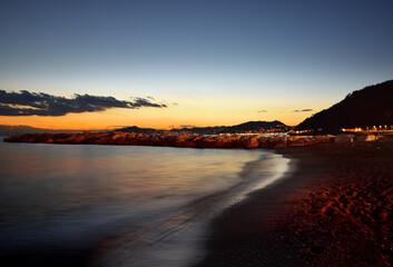 incredible colors and lights, a romantic sunset on the beach facing the sea in the magnificent Liguria