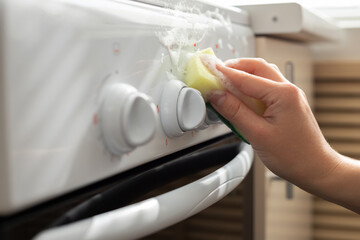Fototapeta na wymiar a woman washes a gas stove with a sponge. close-up