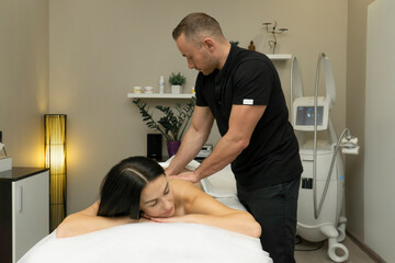 Male masseur doing professional manual back massage using elbows for brunette woman in beauty spa...