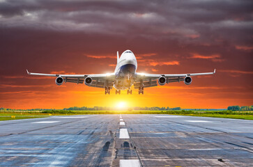 Fototapeta na wymiar Passenger airplane landing at sunset on a runway.