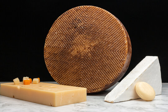 Closeup Image Of A White Akawi, Cheddar And Queso Blanco Cheese And A Small Round Cheese