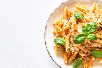 Pasta with tomato sauce, basil and parmesan on white table. Top view with copy space, close up.