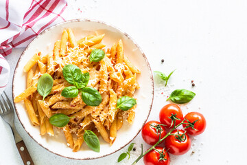 Pasta penne with tomato sauce, basil and parmesan on white table.Top view with copy space.