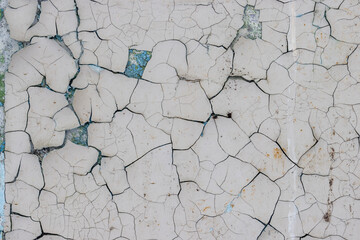 White peeling paint on the wall. Old concrete wall with cracked flaking paint. Weathered rough...