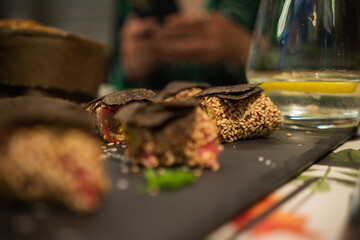 Italian cuisine - caprese with black truffle on a black slate stone in the evening on a table in a restaurant, close-up, selective focus