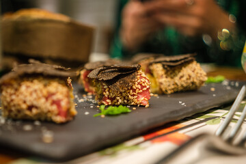 Italian cuisine - caprese with black truffle on a black slate stone in the evening on a table in a restaurant, close-up, selective focus