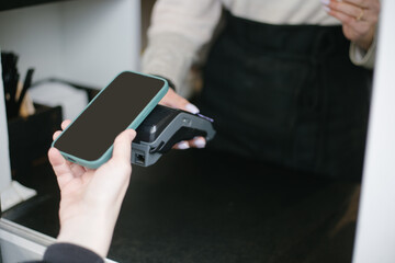 Close-up view of girl using Apple Pay on a iphone paying for purchases
