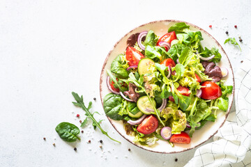 Salad in white plate. Green leaves and vegetables Healthy vegan food, diet food. Top view, copy space.