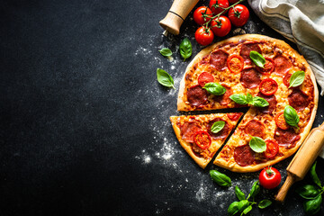 Pizza on black background. Traditional italian pizza with salami cheese, tomatoes and basil. Top...
