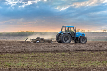 Tractor plowing the field. Beautiful evening sky in background.