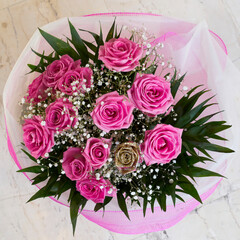 Bright pink and golden roses flower bouquet top view close up, floral festive background