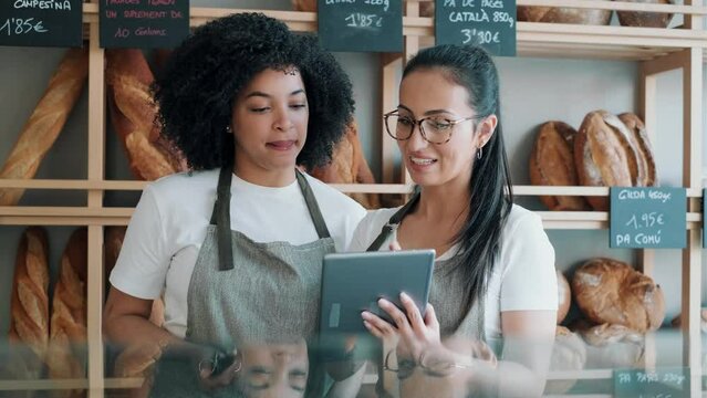 Video of couple women owners bakery working while analyzing report for order delivery with digital tablet in a pastry shop.