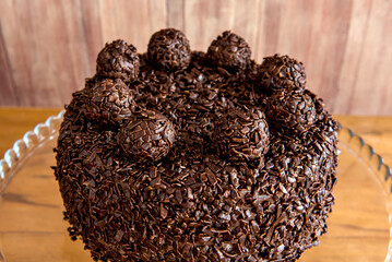 Chocolate cake with brigadeiro grains, delicious dessert on a wooden background close up.