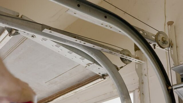 A homeowner handyman type removing an old pulley cable from the garage door opening system in order to install a new one.