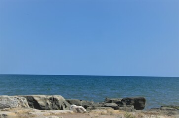 rocky seashore, blue water and blue sky.