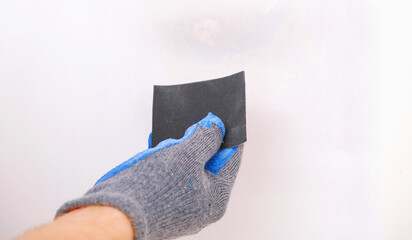 A man cleans old paint on a wooden door with sandpaper. Smoothing out irregularities.