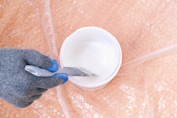 A man stirs white acrylic paint with a special plastic stirrer. Painting the door.
