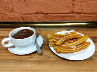 Traditional, typical spanish churros with hot chocolate sauce on a rustic wooden table