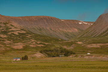 Valley close to Haganes ICeland with crystal clear blue water and some hills and country farms in the background.