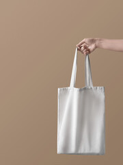Eco bag. Concept photo with copy space. Girl is holding white canvas bag in her hand against beige backdrop