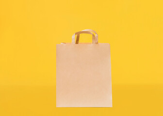 Paper bag. Template with copy space. Kraft bag with handles on yellow backdrop