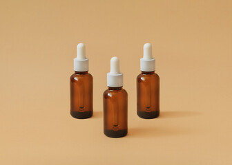 Serum. Photo in minimal style. Three glass bottles with cosmetic product on beige backdrop
