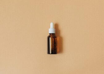 Serum. Top view photo in minimal style. Liquid cosmetic in brown glass bottle on beige backdrop
