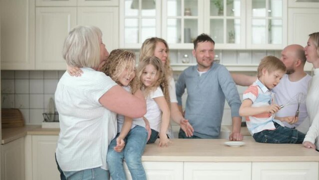 Large family gathered in kitchen of apartment. Three generations together at home. Happy parents with children and grandchildren. relatives talk and laugh. European grandparents babysit grandchildren