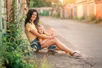 mother and daughter are sitting on the skateboard and  smiling 