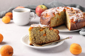 Homemade pie with poppy seeds, apricots and apples with a cup of coffee on a gray background
