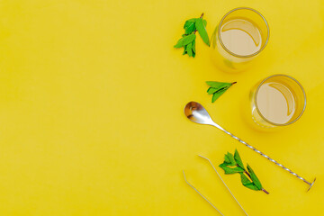 Frozen iced cold orange juice with mint. fresh summer lemonade drinks. Homemade sweet fruit cocktail beverage with bartender tools with copy space on yellow background