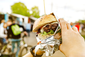 Big burger in hands at street food outdoor festival