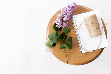 Purple lilac flowers with notebook on wooden background. Morninig, spring, fashion composition. Flat lay, top view.