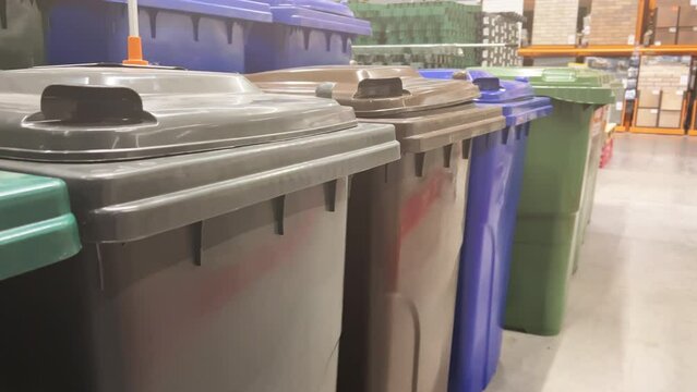 New outdoor plastic dumpsters (trash cans) stand in rows in home improvement store (DIY store)