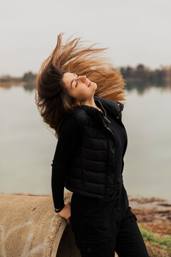 Portrait of a girl moving her hair in the wind by a lake