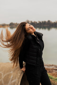 Portrait of a girl moving her hair in the wind by a lake