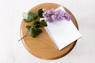 Purple lilac flowers with notebook on wooden background. Morninig, spring, fashion composition. Flat lay, top view.