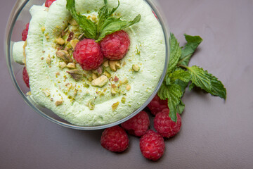 raspberry-pistachio dessert decorated with mint and fresh raspberries