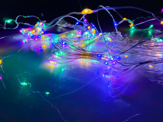 Fototapeta na wymiar Preparing led Garland with colored led lights on a black night background on the mirrored table, showing the colored wires.