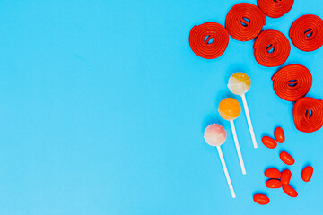 red candies and lollipops on a plain blue background. wallpaper to use text. graphic resource