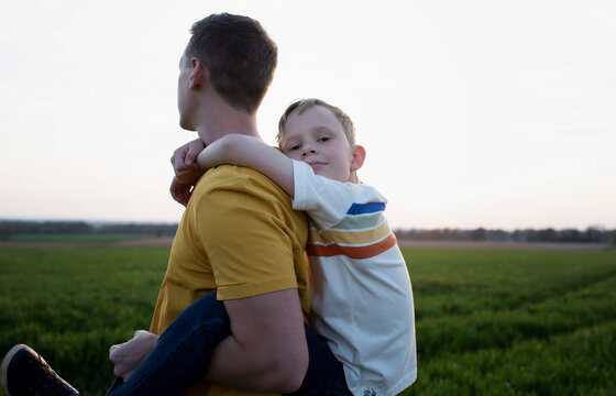 Father Giving Son Piggy Back Ride Wjilst Walking At Sunset