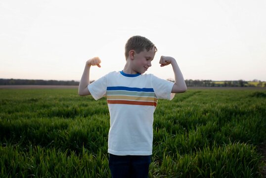 child flexing his muscles whilst outside playing at sunset