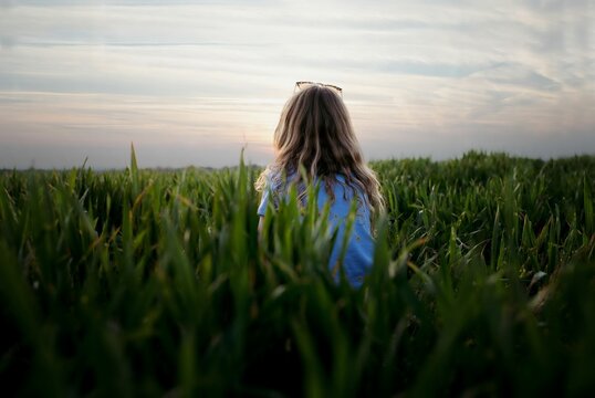 girl sat in a field thinking on her own at watching the sunset