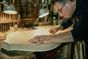 luthier working on a handmade double bass front table in his workshop