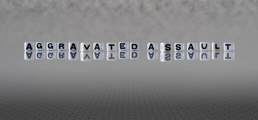 aggravated assault word or concept represented by black and white letter cubes on a grey horizon...