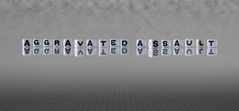 aggravated assault word or concept represented by black and white letter cubes on a grey horizon background stretching to infinity