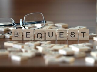 bequest word or concept represented by wooden letter tiles on a wooden table with glasses and a book