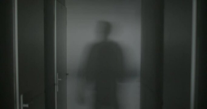 Camera movement, silhouette of a man, shadow on the wall, scratching head with hand, waiting for a meeting in the basement, a secret room. Doors with locks. Psychological discomfort.