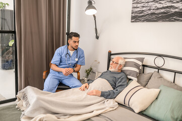 Physician examining a bedridden patient during the home visit