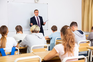 Adult teacher is giving lecture for students in the class